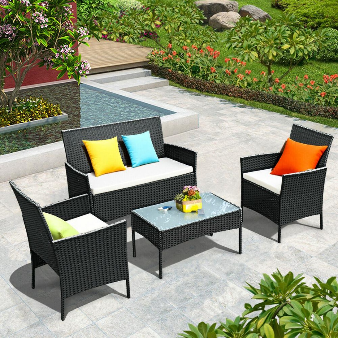 Compacte zwarte rotan loungeset op een stenen terras met kleurrijke kussens.